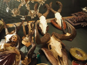 Interior photo of antique shop in Montmartre Paris named L'objet qui Parle showing horned animal skulls, chandeliers, and statutes of French knights