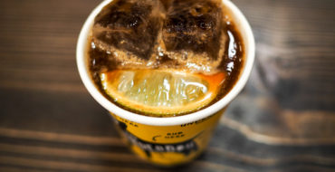Image shows a cup of Underdog Project's Famous Iced Coffee Tonic - Espresso Over Ice, Topped with Tonic and a Fresh Lime Wedge