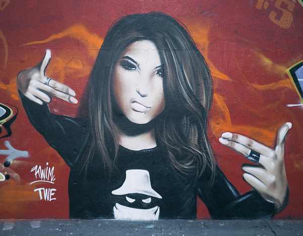 Paris Street Art in Montmartre by Twe Crew showing dark haired young woman with snarl on face making finger guns