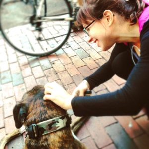 Amanda Phillips bent down and happilly petting Ronin the Boxer dog in Davis Square, summer of 2015